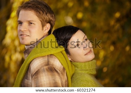 Content couple standing back to back in park, daydreaming in autumn.?
