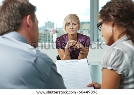 Woman applicant worrying during job interview. Over the shoulder view.