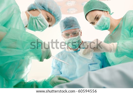 Surgeons and medical assistant wearing mask and uniform operating patient.?