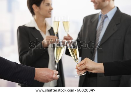 Business people raising toast with champagne at office, focus placed on flutes.