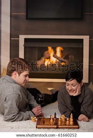 Young couple playing chess at home on a cold winter day.
