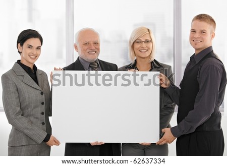 Businessteam holding blank poster for copyspace, smiling, senior executive with young colleagues.?