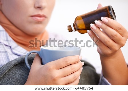 Young woman at home having flu, feeling bad, taking medicine, vitamin, drinking hot tea in bed.?