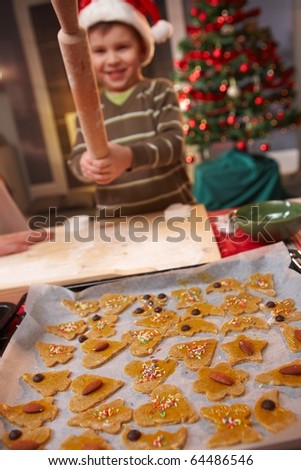 Small boy playing with rolling pin at christmas baking, cake in focus.?