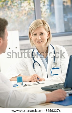Portrait of young doctor in office, having a meeting with patient.