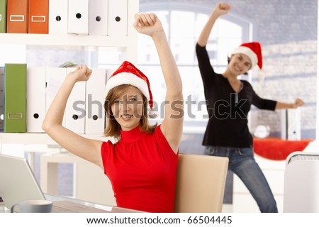 Female office workers having fun in office wearing Santa Claus hat.?