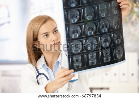 Young attractive female radiologist looking at x-ray image.?