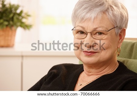 Closeup portrait of older woman wearing glasses, smiling at camera.?