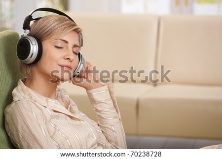 Portrait of smiling woman sitting with eyes closed listening to music on headset.?