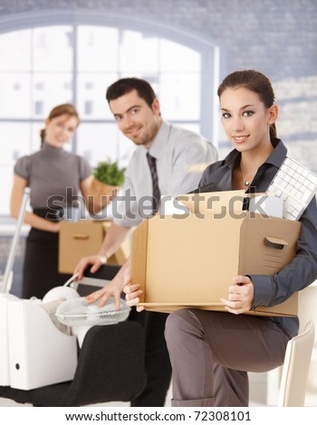 Happy businesspeople moving to new office, packing boxes, smiling.?