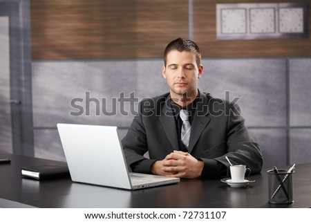 Top manager meditating in elegant office, sitting at desk.?