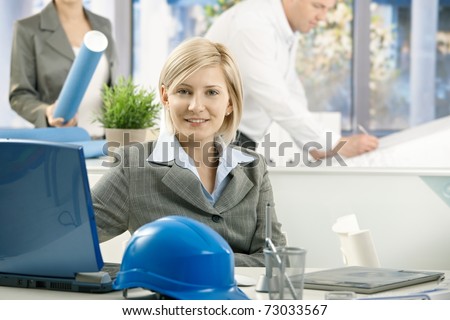 Portrait of mid-adult designer in architect office, smiling at camera,?
