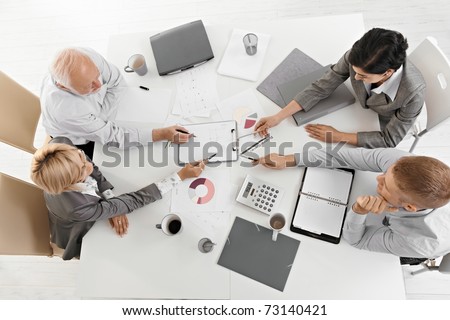 Businesspeople working together at meeting, discussing document on clipboard, high angle view.?