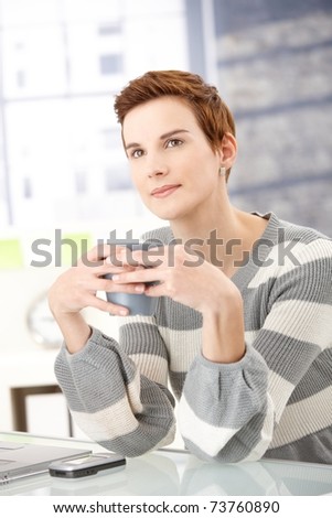 Daydreaming office worker girl sitting at desk with coffee mug handheld.?