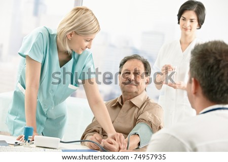 Nurse assisting doctor with measuring patient blood pressure in office.?