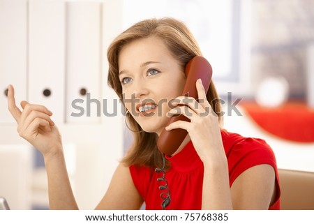 Closeup portrait of attractive office worker, talking on landline phone, gesturing.