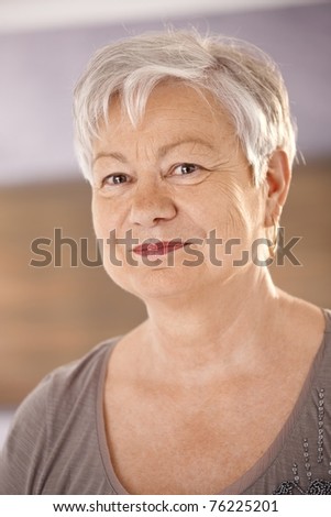 Closeup portrait of elderly woman with white hair, looking at camera, smiling.?