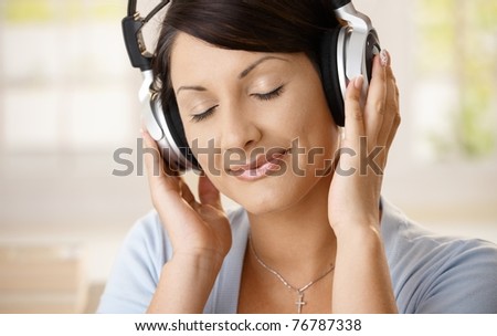 Young woman enjoying music on headphones with closed eyes, smiling.?