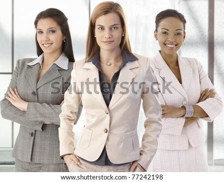 Team portrait of happy businesswomen standing on office corridor, looking at camera, smiling.?