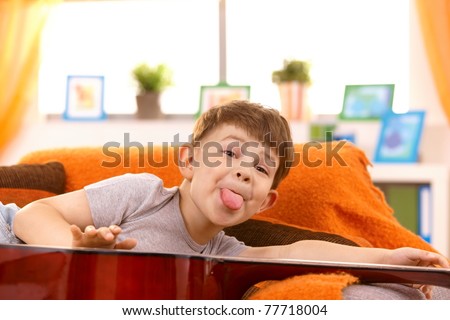 Five year old happy boy putting out tongue for pose in living room.?