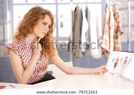 Young attractive fashion designer working in office at desk thinking.?