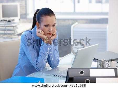 Troubled office worker girl sitting at desk, looking at laptop computer screen, worried.?