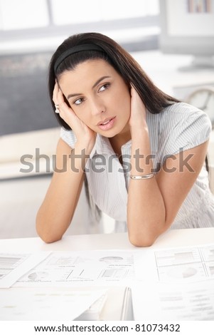 Troubled woman sitting at desk with business documents, thinking.?