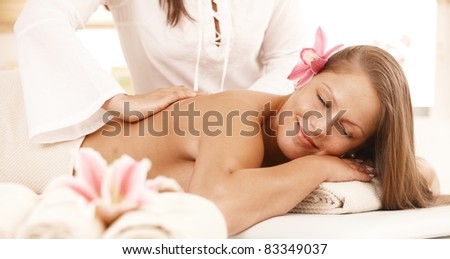 Happy young woman enjoying back massage with closed eyes, smiling.?