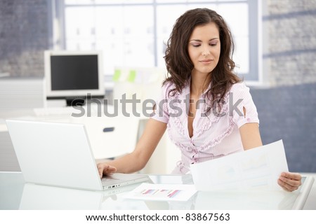 Attractive young secretary working in bright office, using laptop.?