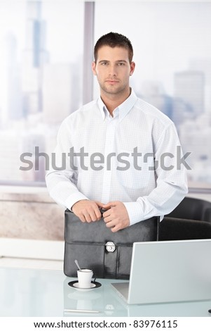 Casual office worker standing in bright office, having briefcase.?
