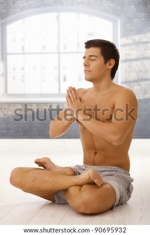 Athletic young man exercising yoga meditation in lotus posture with closed eyes.?