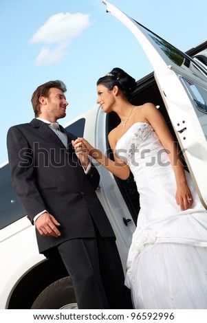 Bride and groom on wedding-day getting out of limousine.?