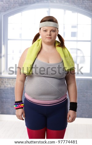 Fat woman standing at the gym in sportswear prepared for doing gymnastics.
