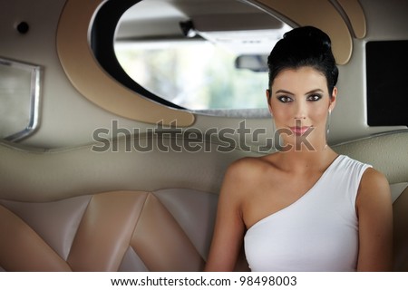 Beautiful elegant young woman sitting in limousine.