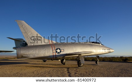 An old jet fighter parked in the desert.