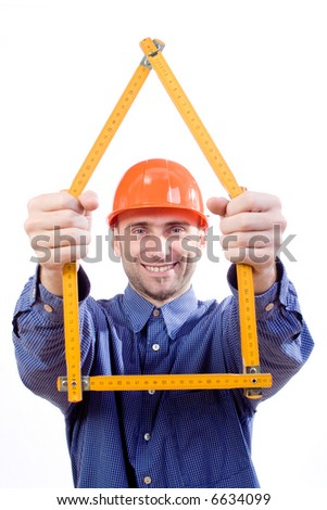 A picture of a man/house designer in a hard hat and business shirt, smiling as he holds up a set of rulers used to form the outline of a house.
