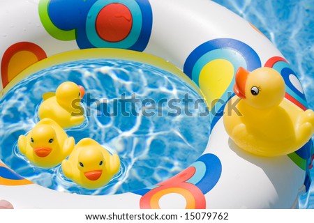 Four toy ducks in the pool waters on a colorful tube depiciting summertime