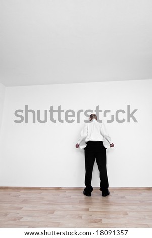 Man in business dress clothes with empty pockets pulled out facing away.