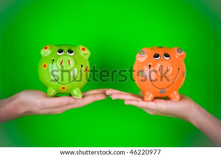 A pair of hands holding ceramic piggy banks.