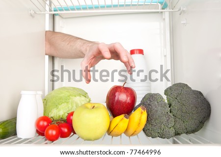 Arm grabbing apple from inside refrigerator.