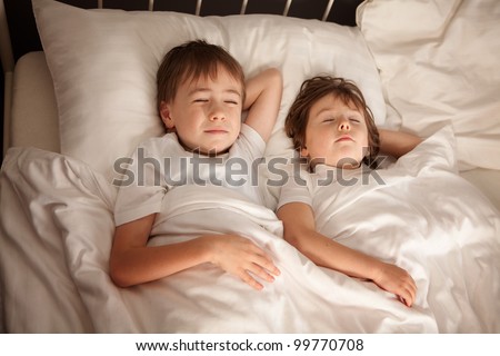 Cute young preschool brother and sister sleeping together in bed.