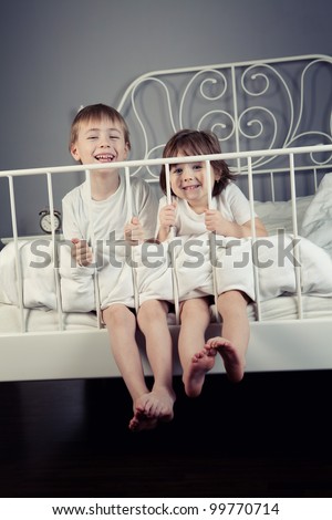 Brother and Sister in their parents bed pulling funny faces.
