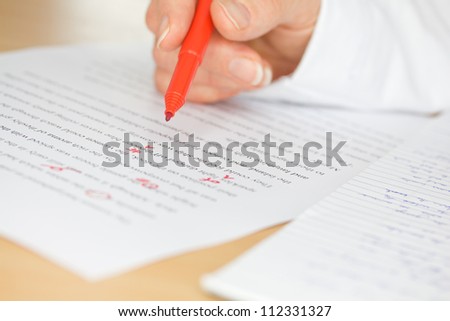 Proofreader with red pen checks a transcription of some hand written text