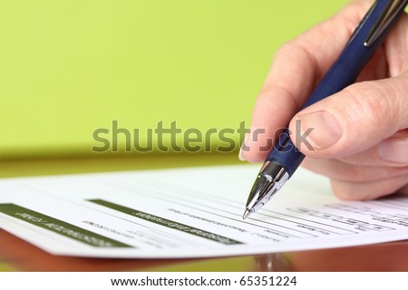 Hand with Pen Signing Form Closeup on Green Background