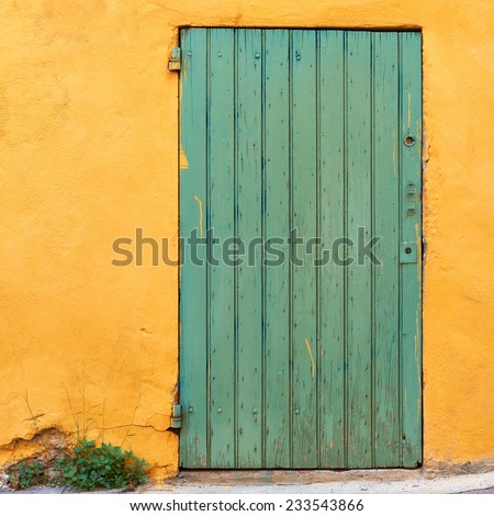 Green door on yellow wall in French village, typical colors of Provence