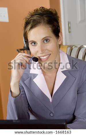 Model Release 352  Woman in early 20s working on computer and talking on headset telephone at home