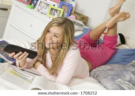Teenage girl watching TV while doing homework