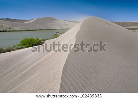 Natural Sand dune has wind blowing sand from the top