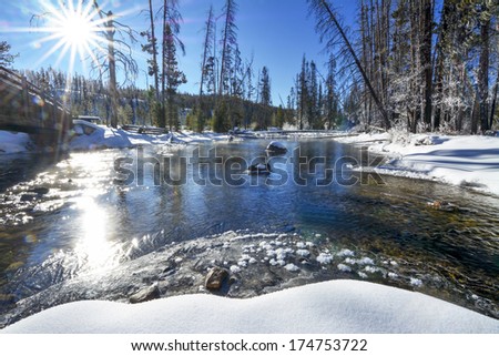 Sun-star and wild river in winter with bridge
