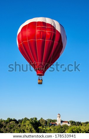 Huge hot air balloon over a city part with a depot